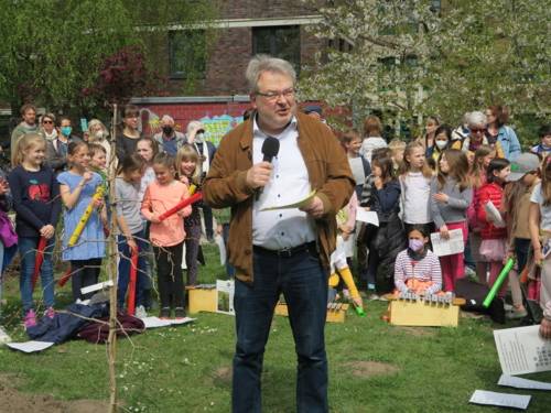 Bürgermeister Thomas Hermann hält ein Grußwort, im Hintergrund Kinder der Südstadtschule